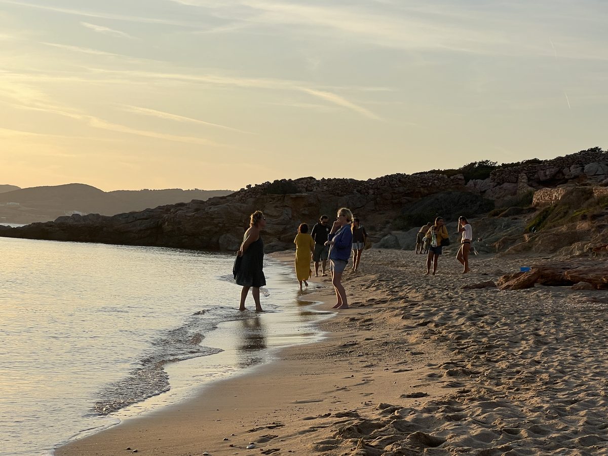 Retreat guests walking along a Paros beach at golden hour