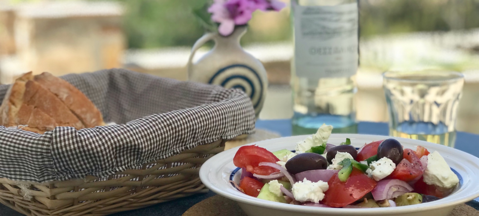 Fresh bread, Greek salad and local wine on a terrace table, Paros